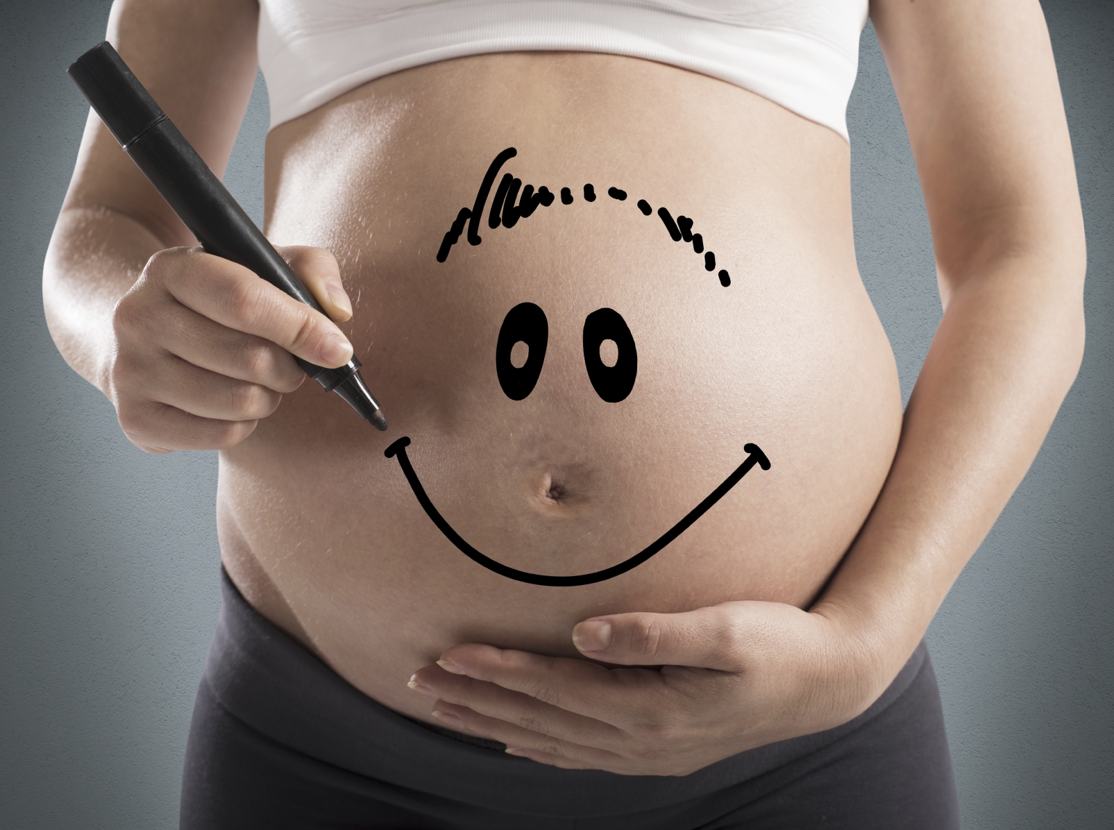 Smiley drawn on a pregnant woman stomach